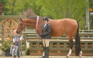 Holly Orlando and William Hill in their winner's presentation with Holly's daughter, Logan; photo © The Book LLC