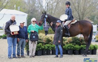 Keirstin Johnsen and Hennepin, along with owner Shelly Ferrall and groom Fidel Ventura, are awarded with the champion ribbon, as well as the Debby Malloy Winkler Memorial Trophy, donated by the Malloy Family and presented by Vivien and Mark Malloy; photo © Jump Media